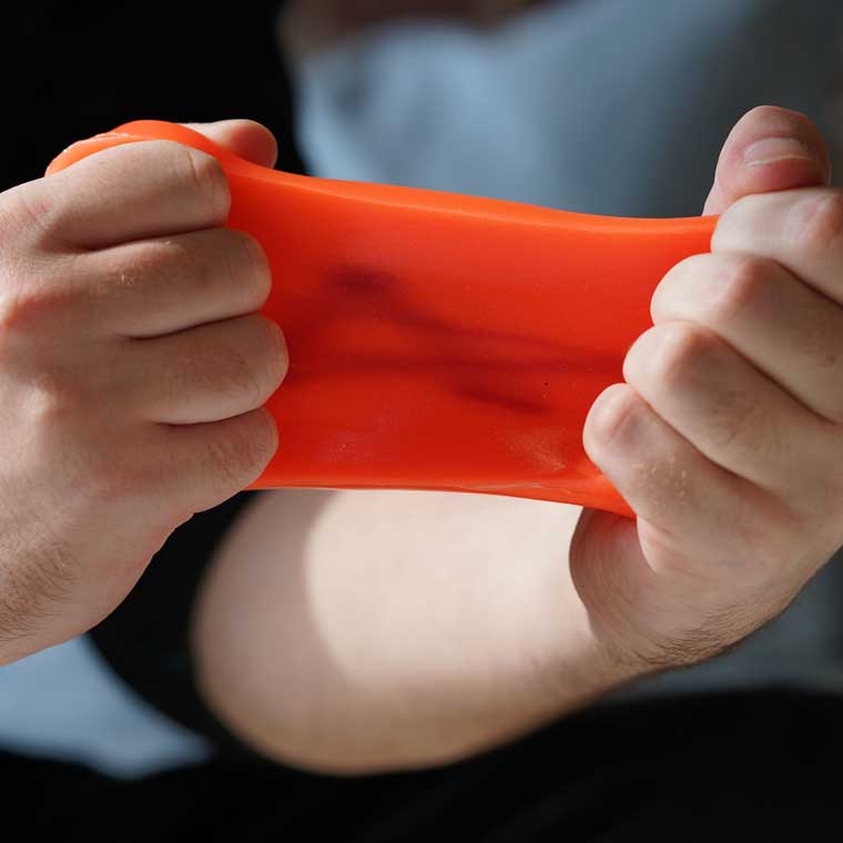 Two hands stretching orange glow putty.