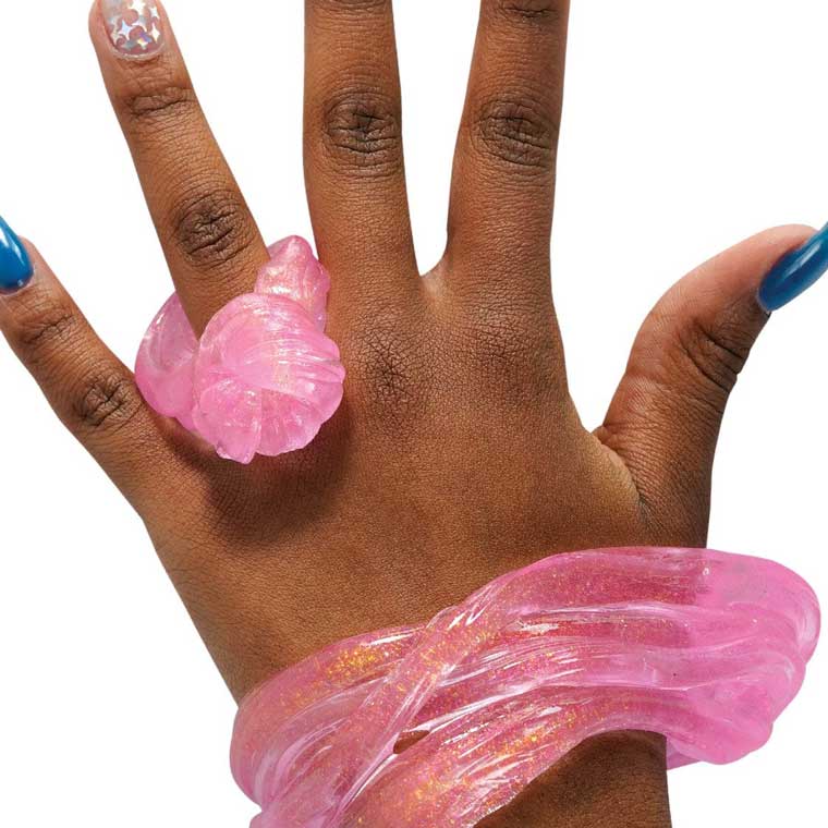 Hand with clear pink putty sculpted into a ring and bracelet.